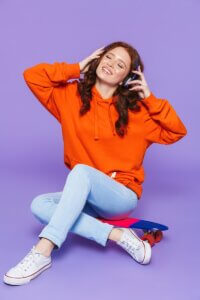 a woman sitting on the ground with a cell phone to her ear